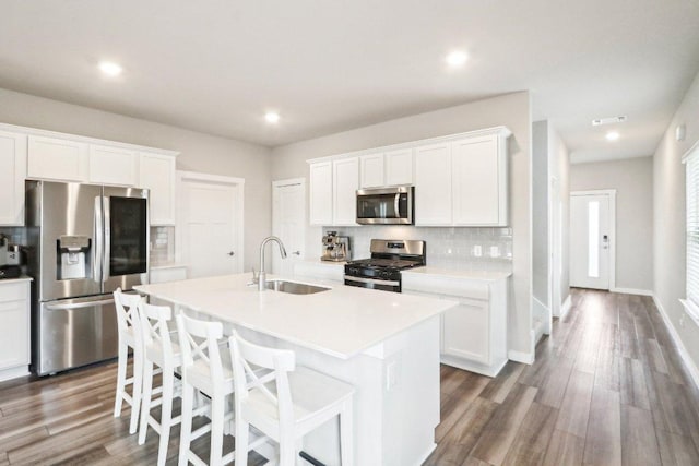 1208 Tipton St, Georgetown, TX 78633 - kitchen with appliances with stainless steel finishes, a sink, decorative backsplash, an island with sink, and white cabinets