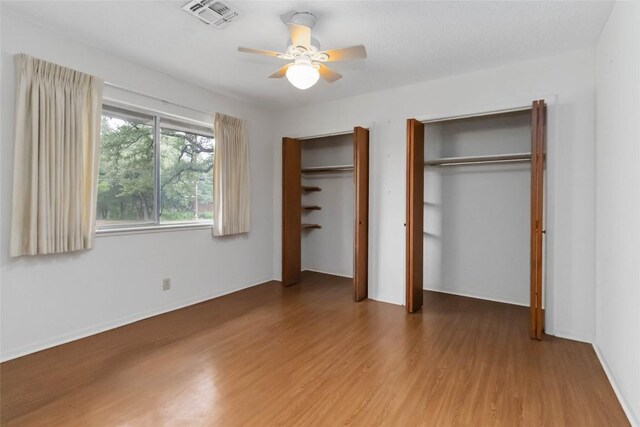 1402 Brown St, San Marcos, TX 78666 - unfurnished bedroom featuring visible vents, a ceiling fan, multiple closets, and wood finished floors