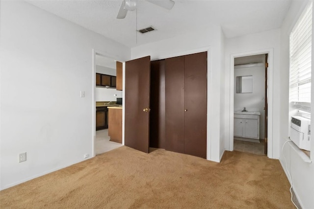 1402 Brown St, San Marcos, TX 78666 - unfurnished bedroom featuring visible vents, a closet, ensuite bathroom, light colored carpet, and a ceiling fan
