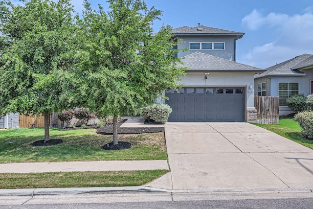 view of front facade with fence, a front lawn, a garage, stucco siding, and driveway