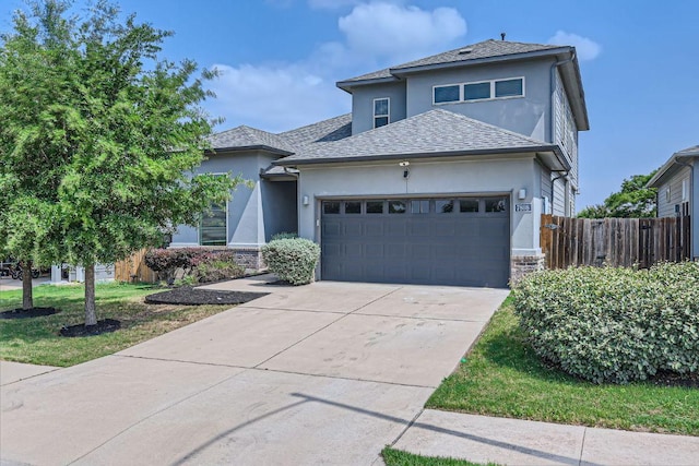 prairie-style home featuring a garage, stucco siding, stone siding, and fence