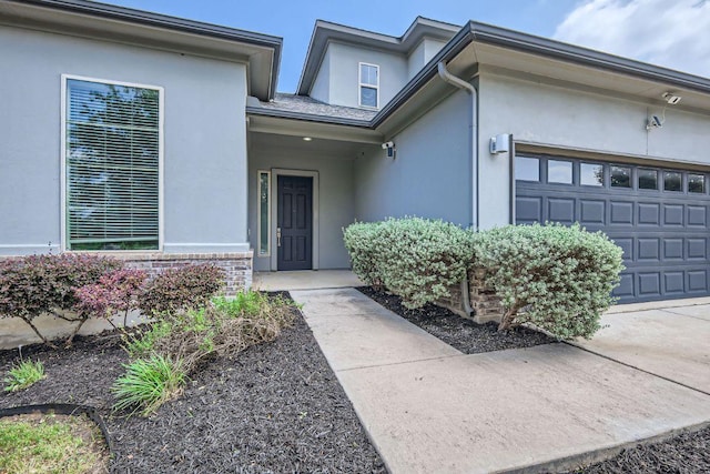 entrance to property with a garage and stucco siding