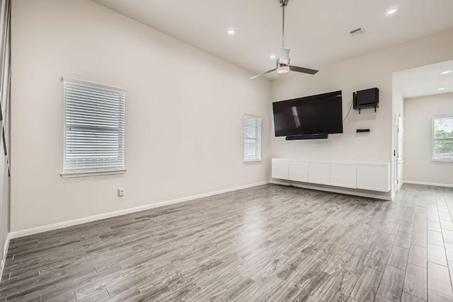 unfurnished living room with a ceiling fan, baseboards, recessed lighting, and wood finished floors