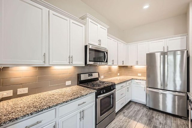 kitchen featuring white cabinetry, appliances with stainless steel finishes, decorative backsplash, and light stone counters