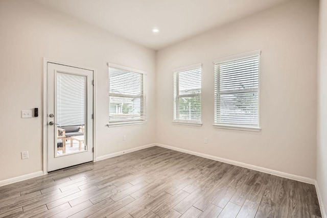 empty room with recessed lighting, baseboards, and wood finished floors