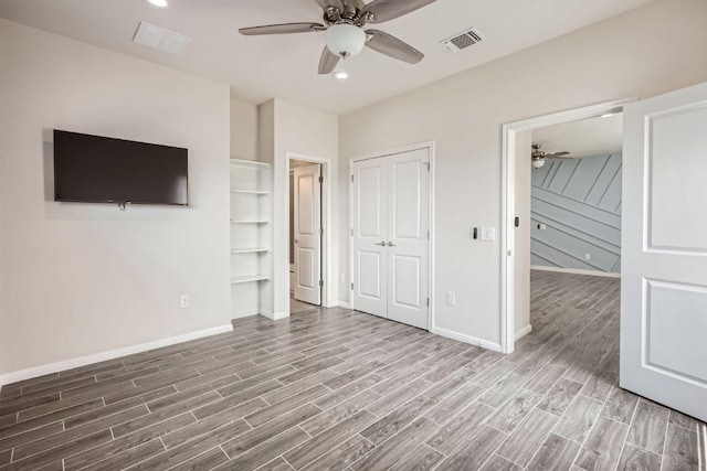 unfurnished bedroom featuring baseboards, wood finished floors, and visible vents