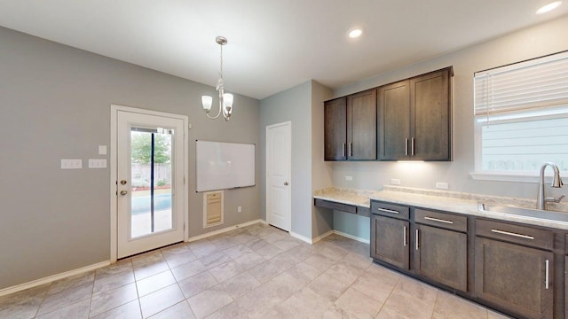 387 Gustaf Trl, Kyle, TX 78640 - kitchen featuring dark brown cabinets, a chandelier, built in desk, decorative light fixtures, and light tile patterned floors