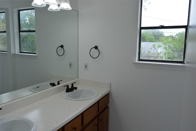 bathroom featuring double vanity, a chandelier, and a sink