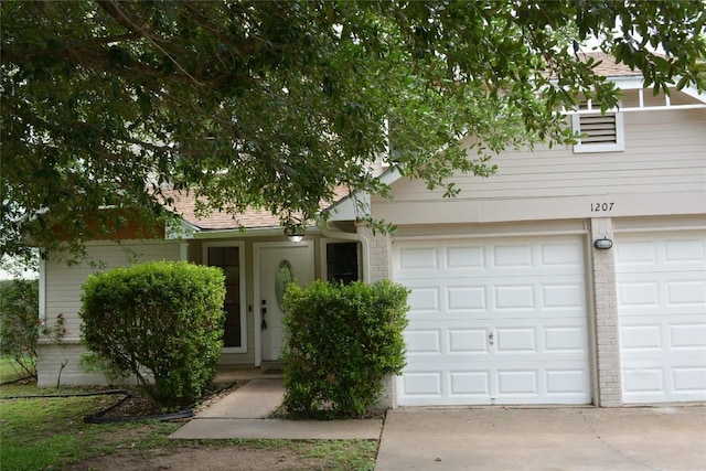 view of property hidden behind natural elements featuring concrete driveway