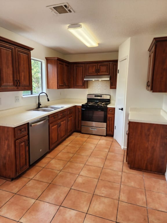 kitchen with visible vents, light countertops, under cabinet range hood, a sink, and appliances with stainless steel finishes