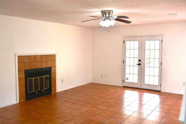 unfurnished living room with ceiling fan, a fireplace, french doors, and a textured ceiling