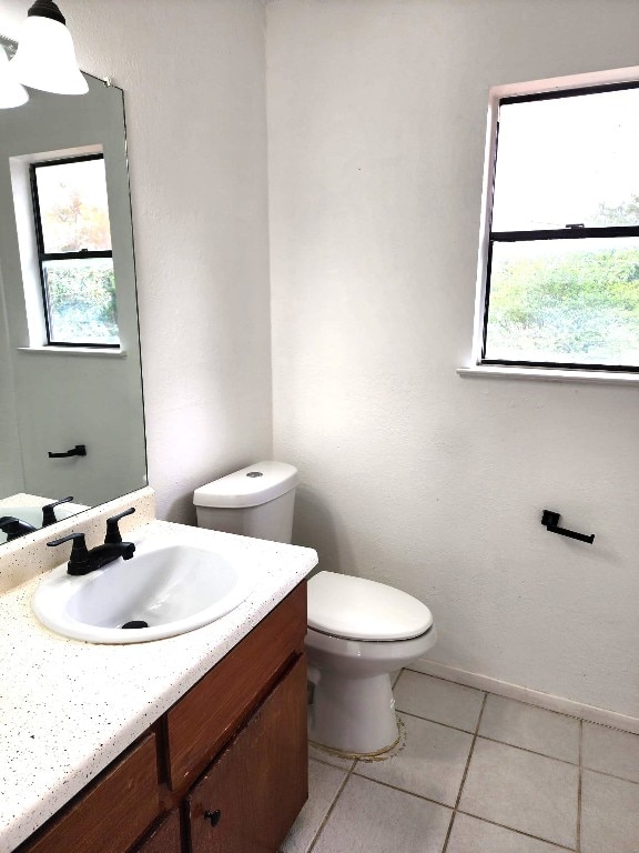 bathroom with tile patterned flooring, a healthy amount of sunlight, toilet, and vanity