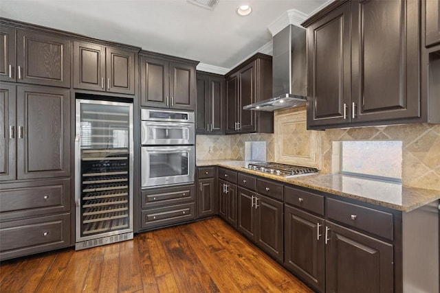 3109 Brigham Ct, Austin, TX 78732 - kitchen featuring wine cooler, dark brown cabinets, wall chimney exhaust hood, light stone counters, and appliances with stainless steel finishes