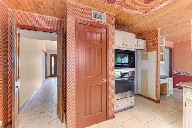 kitchen with visible vents, black microwave, oven, wooden ceiling, and light tile patterned floors