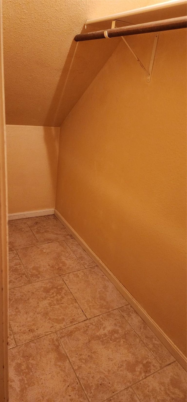 spacious closet with light tile patterned flooring and vaulted ceiling