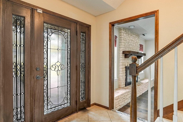 entryway with baseboards, stairs, and light tile patterned floors