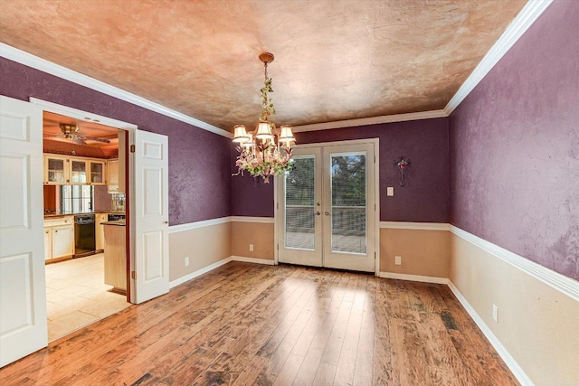 unfurnished dining area featuring french doors, light wood-style flooring, crown molding, and a chandelier