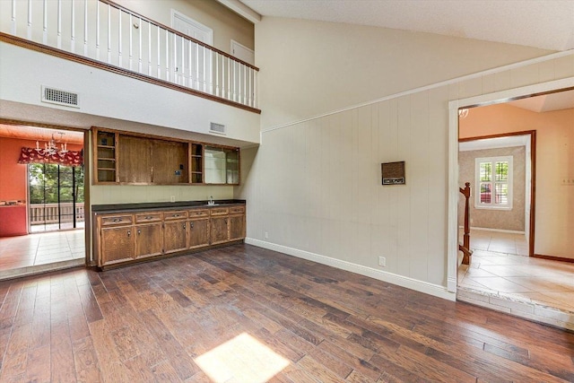 unfurnished living room featuring a healthy amount of sunlight, baseboards, dark wood-style flooring, and visible vents