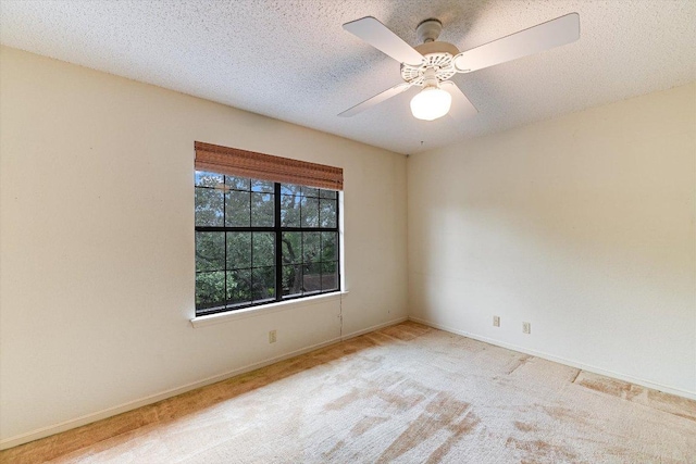 carpeted empty room featuring baseboards, a ceiling fan, and a textured ceiling