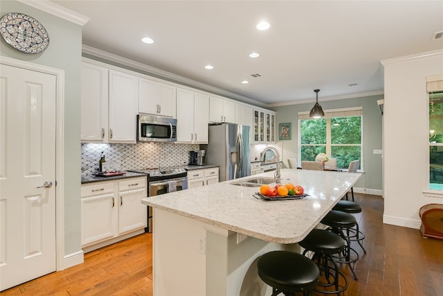 712 Independence Creek Ln, Georgetown, TX 78633 - kitchen featuring decorative backsplash, ornamental molding, a center island with sink, a sink, and stainless steel appliances