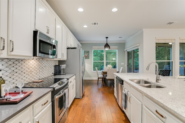 712 Independence Creek Ln, Georgetown, TX 78633 - kitchen with visible vents, ornamental molding, a sink, light wood-style flooring, and stainless steel appliances
