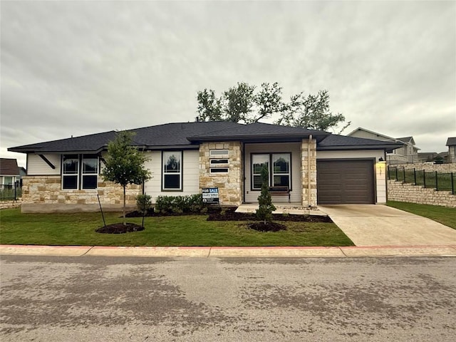 prairie-style home with a garage, fence, driveway, and stone siding