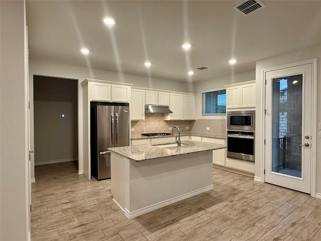 kitchen featuring under cabinet range hood, stainless steel appliances, light wood-type flooring, and visible vents