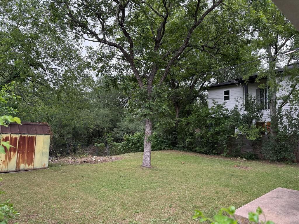view of yard with a storage shed, fence, and an outdoor structure