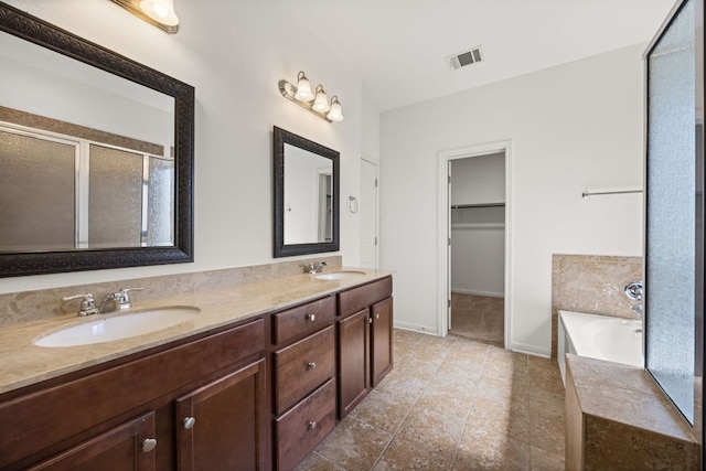 bathroom with double vanity, a garden tub, visible vents, a shower stall, and a sink