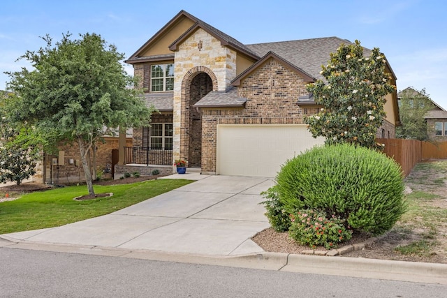 traditional-style home with a front lawn, fence, roof with shingles, brick siding, and driveway