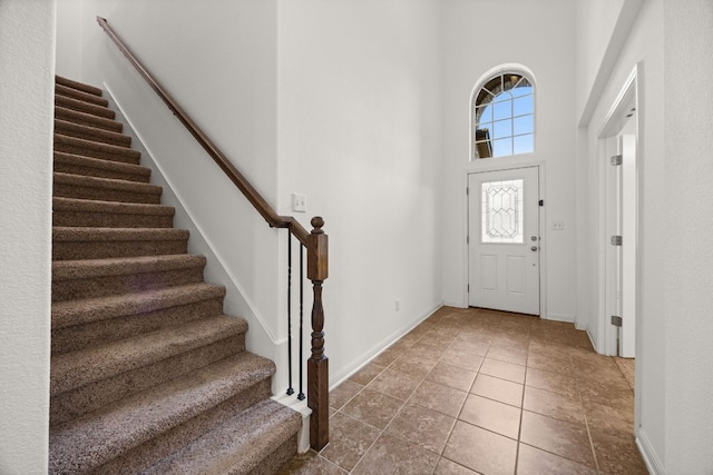 entryway with baseboards, a towering ceiling, and stairway