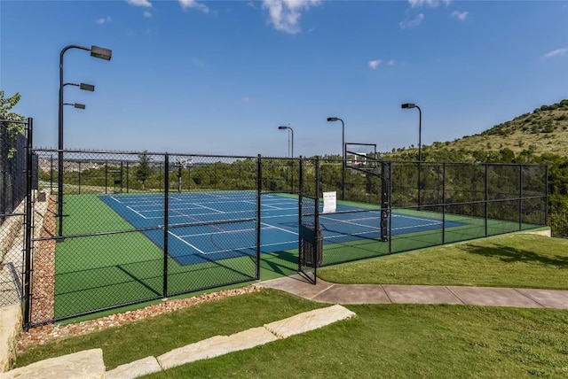 view of sport court featuring fence, a tennis court, and a yard