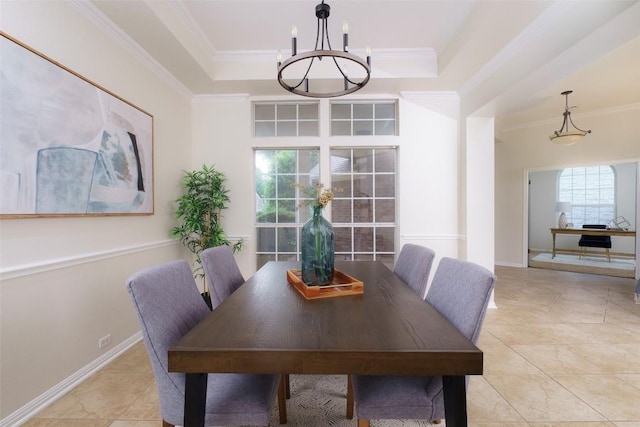dining space with light tile patterned floors, a raised ceiling, baseboards, a notable chandelier, and ornamental molding