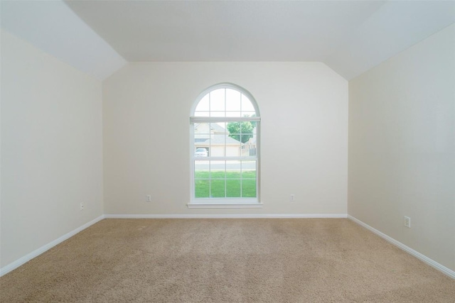 unfurnished room featuring light colored carpet, baseboards, and vaulted ceiling