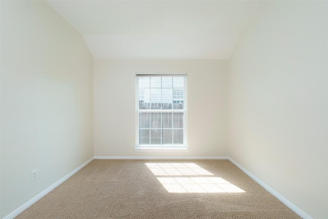 empty room featuring baseboards, carpet, and lofted ceiling