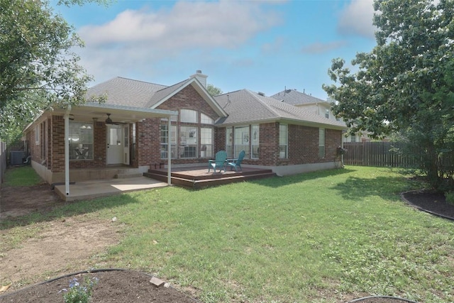 rear view of property with fence, a chimney, a lawn, and brick siding