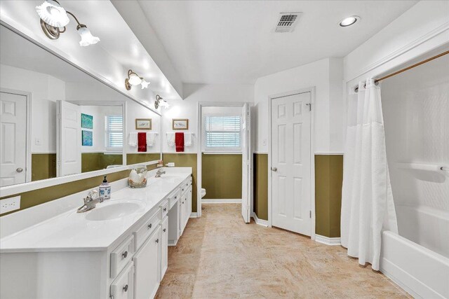 full bathroom with a sink, toilet, double vanity, and visible vents