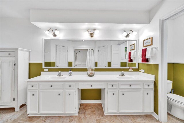 bathroom featuring double vanity, a sink, and toilet