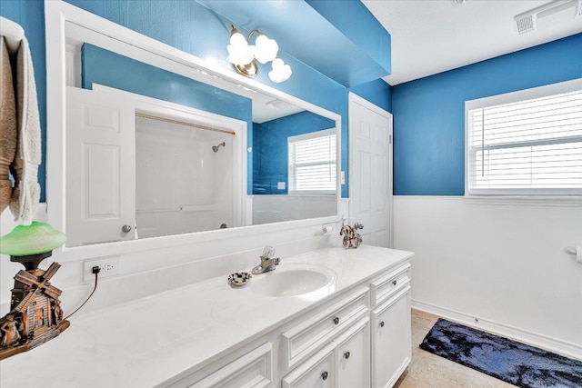 bathroom with vanity, a shower, visible vents, and a healthy amount of sunlight