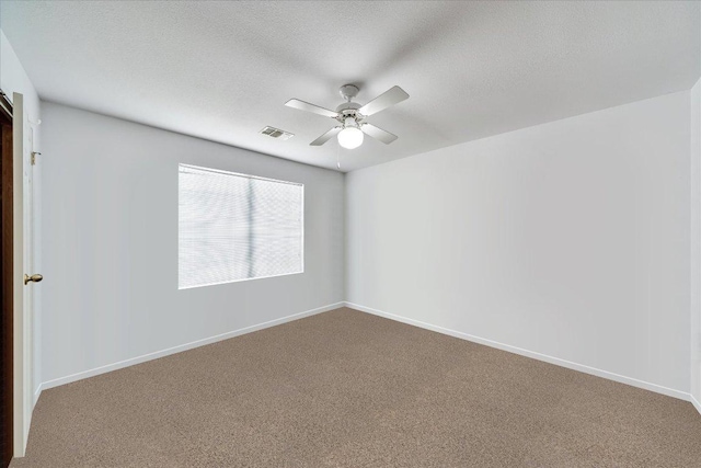 empty room with carpet floors, a ceiling fan, baseboards, and visible vents