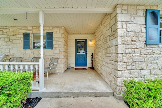 doorway to property with covered porch and stone siding
