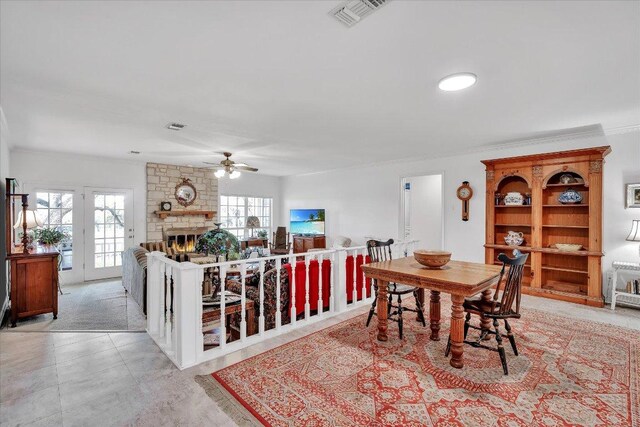 dining room featuring crown molding, a ceiling fan, visible vents, and a fireplace