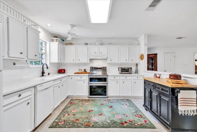 kitchen featuring range with two ovens, dishwasher, a sink, light countertops, and white cabinets