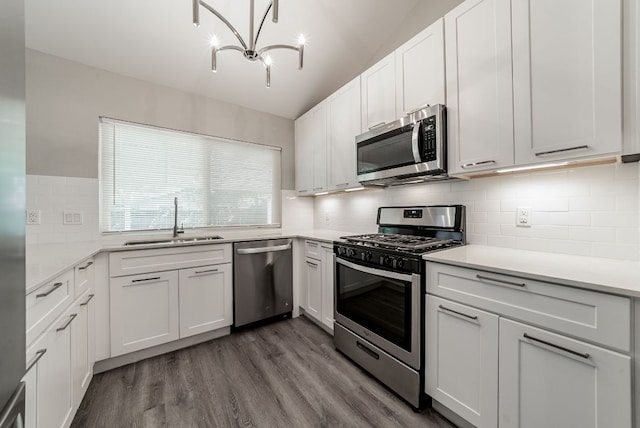 10429 Firethorn Ln, Austin, TX 78750 - kitchen with backsplash, appliances with stainless steel finishes, a sink, dark wood-style floors, and a notable chandelier