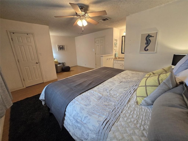 bedroom with visible vents, connected bathroom, a textured ceiling, and ceiling fan