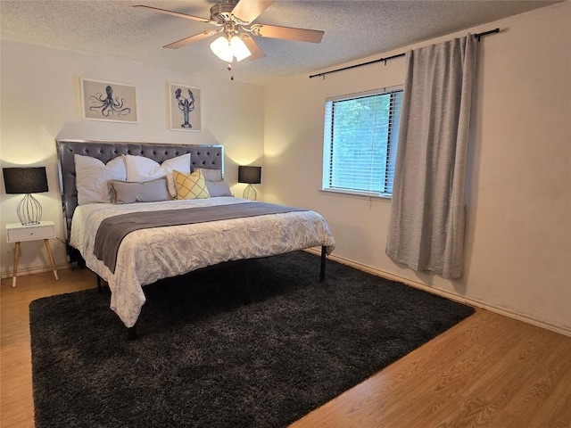 bedroom with ceiling fan, a textured ceiling, and wood finished floors