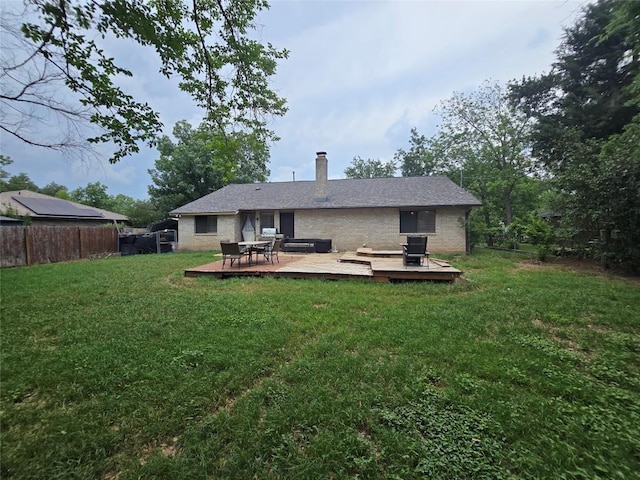 back of house with fence, brick siding, a wooden deck, a chimney, and a yard