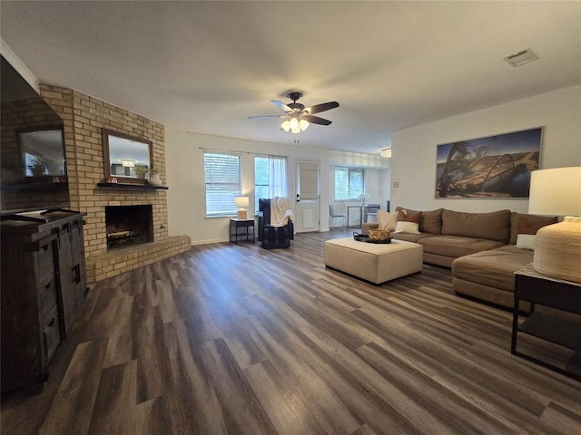 living room featuring a fireplace, a ceiling fan, baseboards, dark wood-type flooring, and visible vents