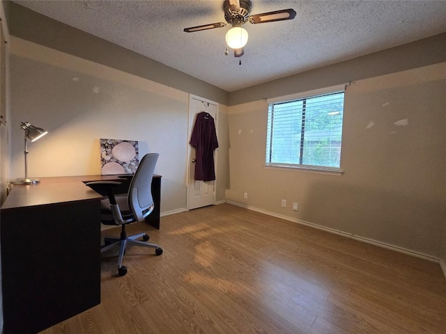 office space featuring baseboards, a ceiling fan, a textured ceiling, and wood finished floors