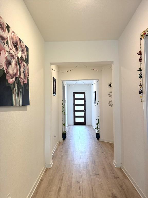 hallway featuring baseboards and light wood-style flooring